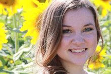 Rebekah Hadeen stands in front of giant sunflowers.