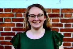 Michelle Collver smiling in front of a brick wall.