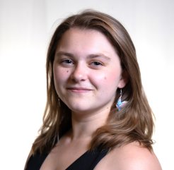 Shayla Pominville, with shoulder-length brown hair, smiles at the camera.