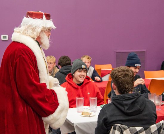 Santa Claus visits with students at the 2025 Holiday Dinner.