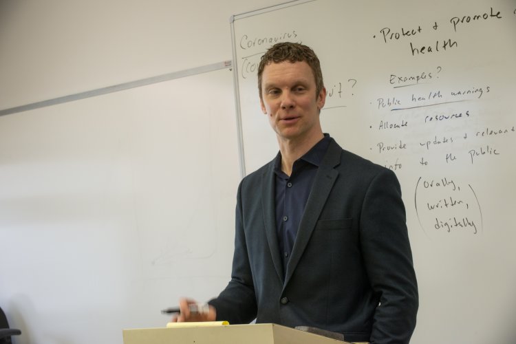 Luke Perrry at a lectern in the classroom.